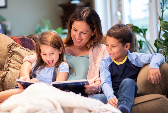 A mother sitting with her 2 kids reading 7 Books about surrogacy